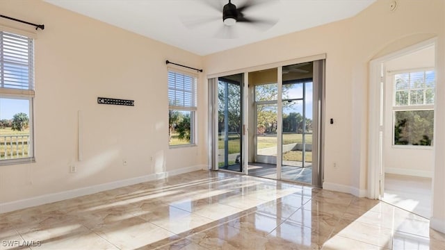 spare room with a healthy amount of sunlight, marble finish floor, and baseboards