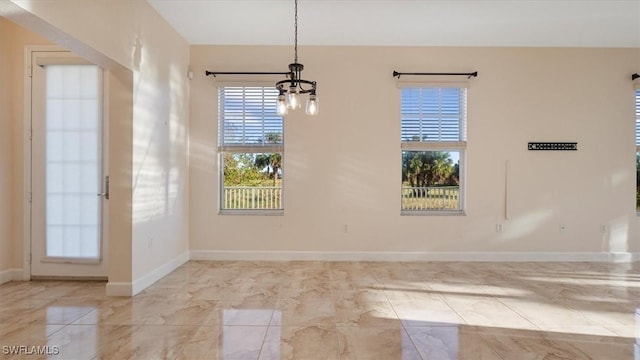 unfurnished dining area with a notable chandelier and baseboards