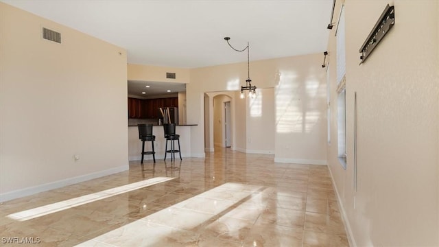 unfurnished room featuring visible vents, arched walkways, marble finish floor, and baseboards