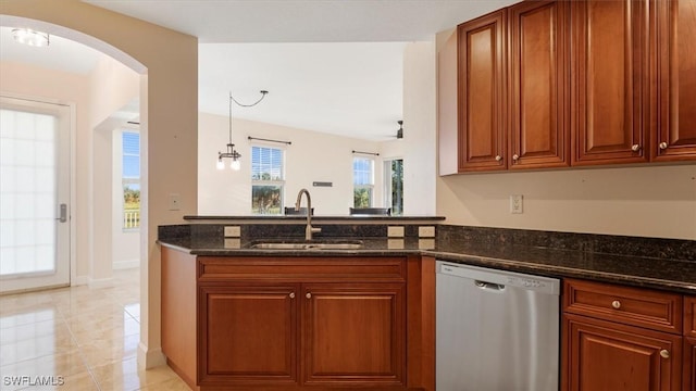 kitchen featuring a sink, dark stone countertops, stainless steel dishwasher, arched walkways, and a peninsula