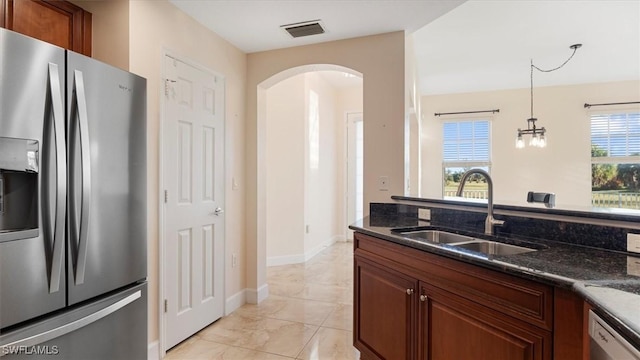 kitchen with stainless steel refrigerator with ice dispenser, a sink, dark stone countertops, arched walkways, and white dishwasher