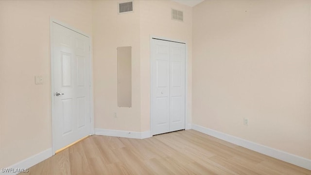 unfurnished bedroom with baseboards, visible vents, a closet, and light wood-type flooring