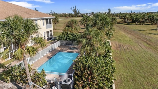 community pool featuring a rural view, central AC unit, a yard, and fence