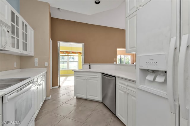 kitchen with kitchen peninsula, white appliances, sink, light tile patterned floors, and white cabinetry