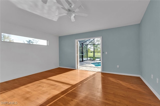 spare room featuring ceiling fan, hardwood / wood-style floors, and a healthy amount of sunlight