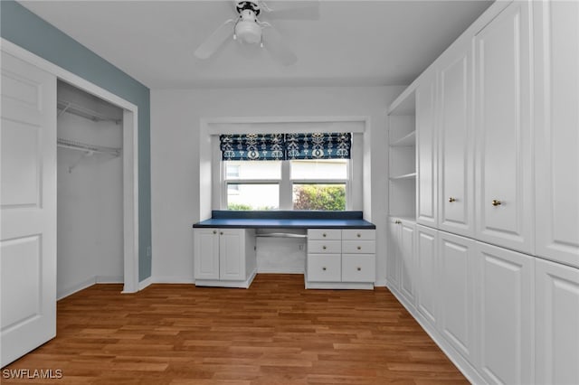 unfurnished office featuring ceiling fan, light hardwood / wood-style flooring, and built in desk