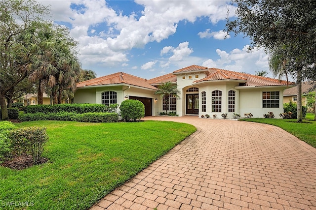 mediterranean / spanish home with a front lawn, a garage, and french doors