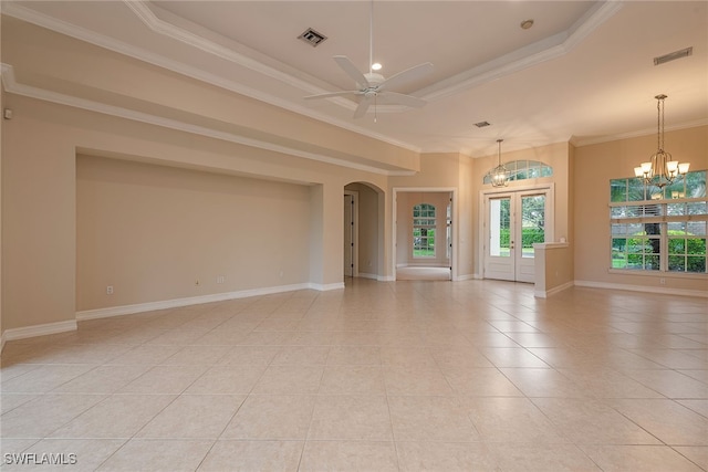 empty room with light tile patterned floors, ceiling fan with notable chandelier, a tray ceiling, and ornamental molding