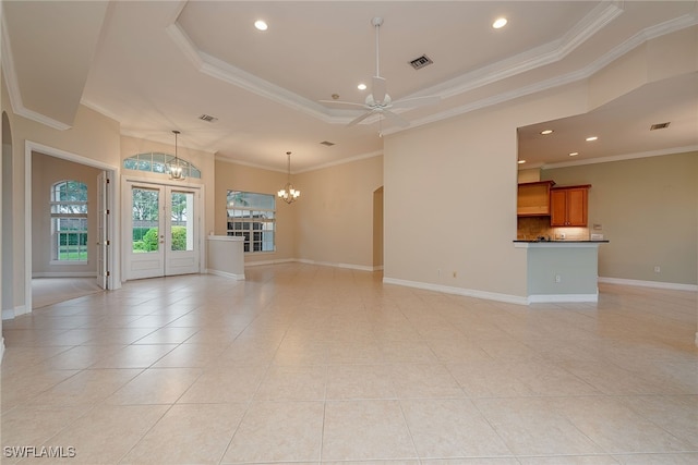 unfurnished living room with ceiling fan with notable chandelier, a raised ceiling, crown molding, and light tile patterned flooring