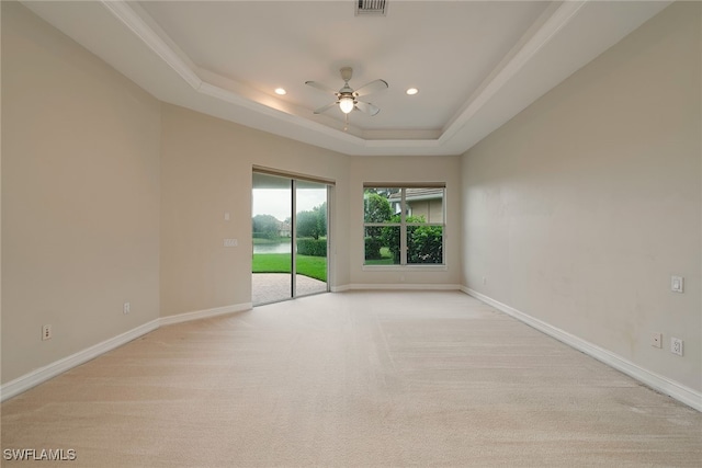 empty room featuring a tray ceiling, light carpet, and ceiling fan