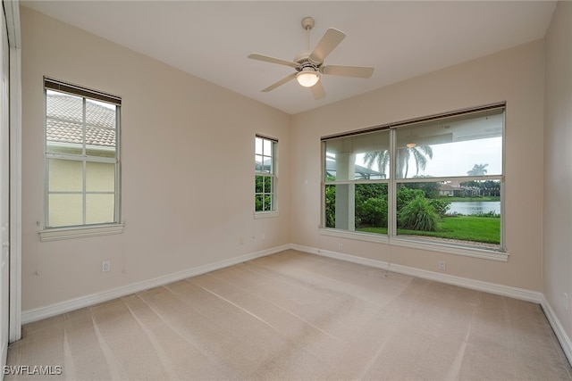 carpeted empty room with ceiling fan and a water view