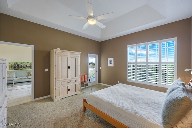 bedroom featuring ceiling fan, light colored carpet, a tray ceiling, and multiple windows