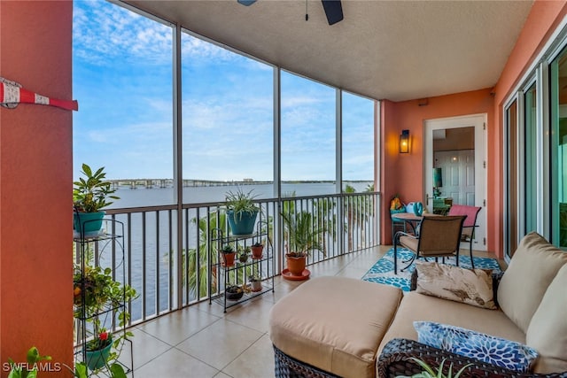 sunroom / solarium featuring a water view and ceiling fan