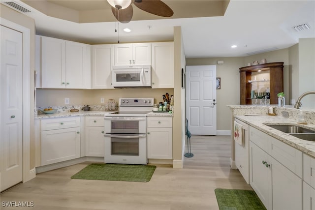 kitchen featuring white appliances, light wood finished floors, visible vents, white cabinetry, and a sink