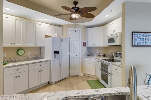 kitchen featuring light wood-style flooring, recessed lighting, white appliances, white cabinetry, and a tray ceiling