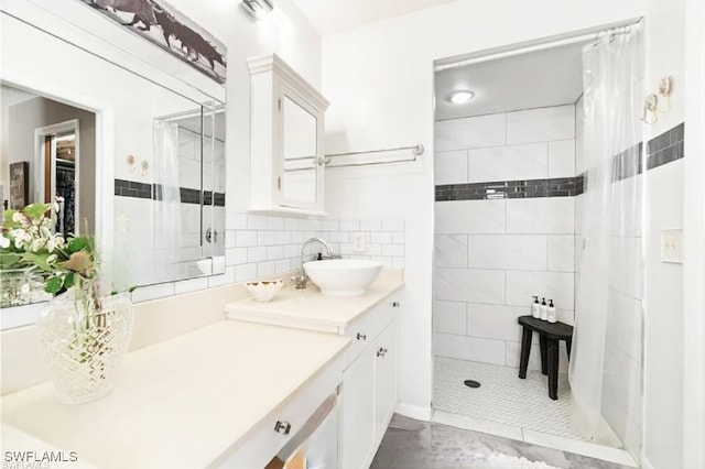 bathroom with a tile shower, vanity, and backsplash