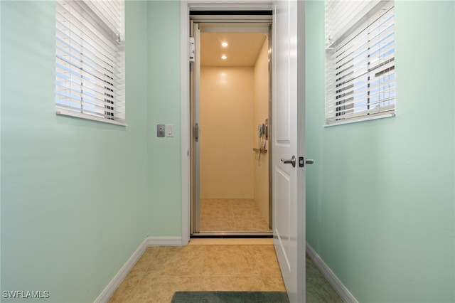 corridor with elevator and light tile patterned floors