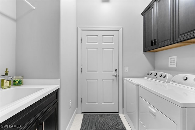 laundry area featuring cabinets, washing machine and dryer, and light tile patterned flooring