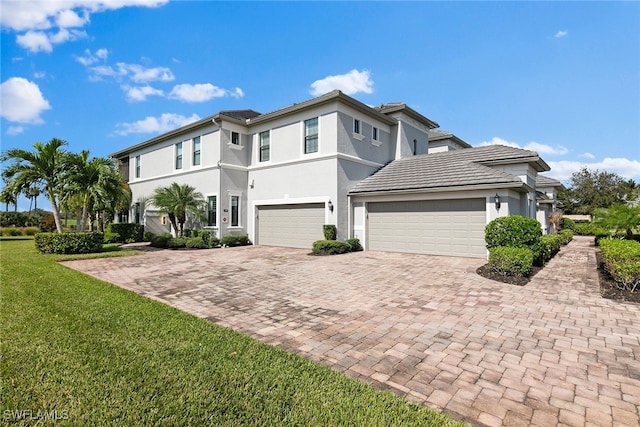 view of front of house with decorative driveway, a front lawn, and stucco siding