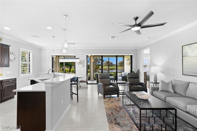 tiled living room featuring ceiling fan, crown molding, sink, and a wealth of natural light