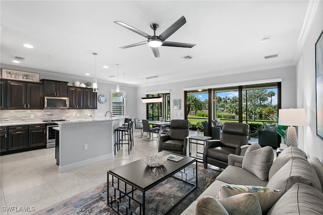 living room with ceiling fan, light tile patterned flooring, sink, and crown molding