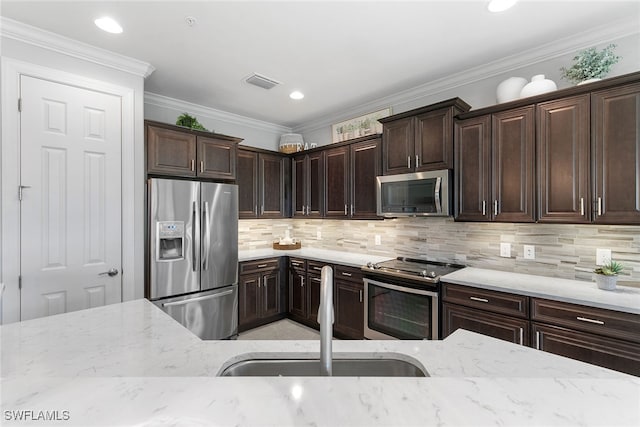 kitchen featuring dark brown cabinetry, crown molding, sink, and stainless steel appliances