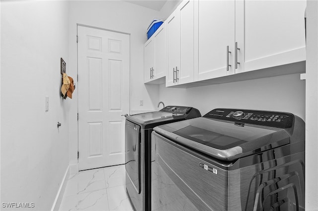 clothes washing area featuring cabinets and washing machine and clothes dryer