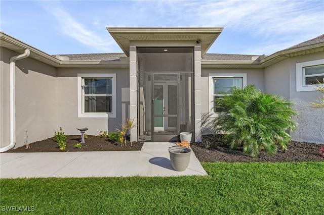 view of exterior entry featuring a lawn