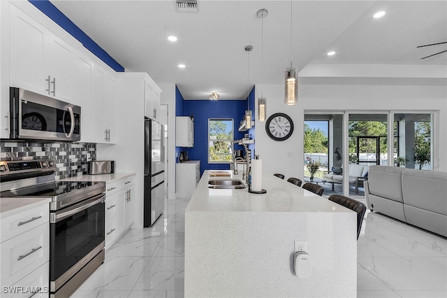 kitchen with a center island with sink, white cabinetry, sink, and appliances with stainless steel finishes