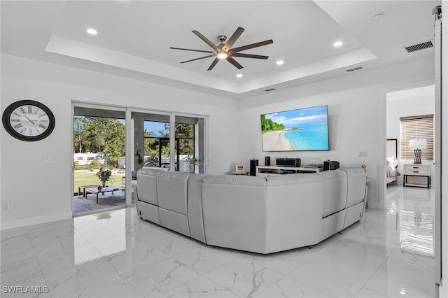 living room featuring a raised ceiling and ceiling fan