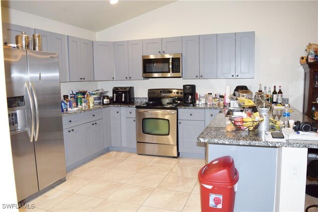 kitchen with kitchen peninsula, appliances with stainless steel finishes, vaulted ceiling, and gray cabinetry