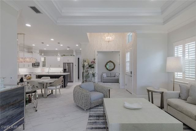 living room featuring a notable chandelier, sink, and crown molding