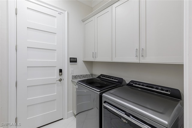 clothes washing area featuring washing machine and dryer and cabinets