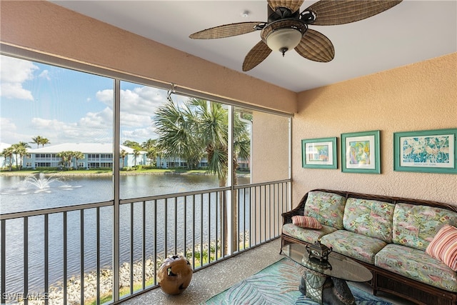 sunroom featuring ceiling fan and a water view