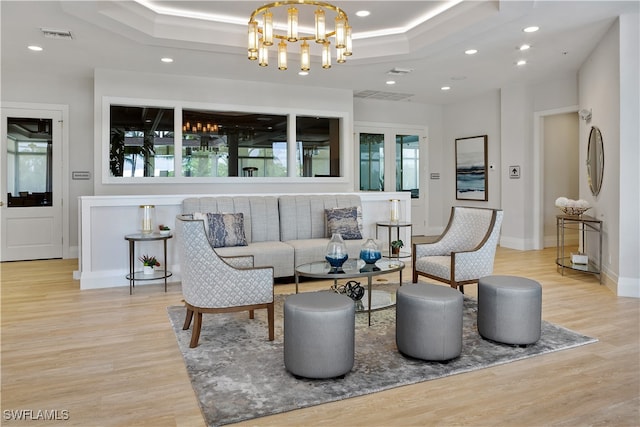 living room with a raised ceiling, light hardwood / wood-style flooring, and a healthy amount of sunlight