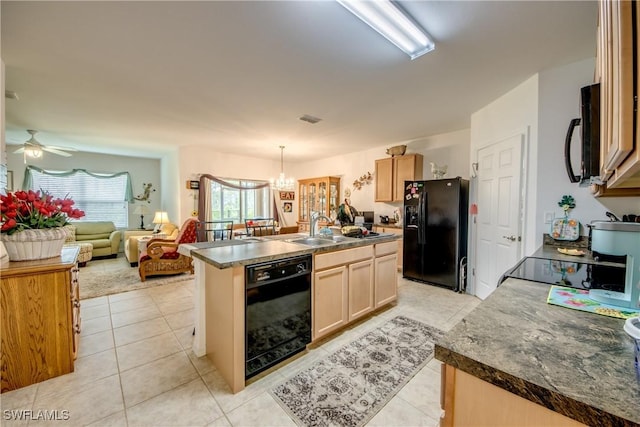 kitchen with sink, an island with sink, pendant lighting, black appliances, and ceiling fan with notable chandelier