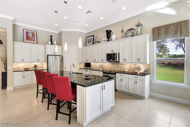 kitchen featuring a center island with sink, white cabinets, and stainless steel appliances