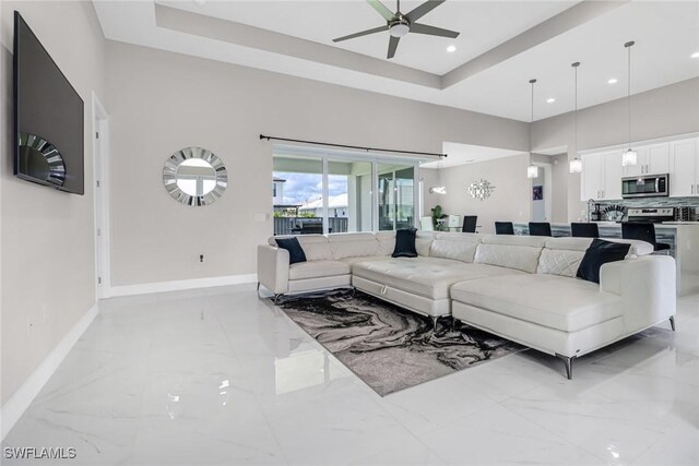 living room with a tray ceiling and ceiling fan