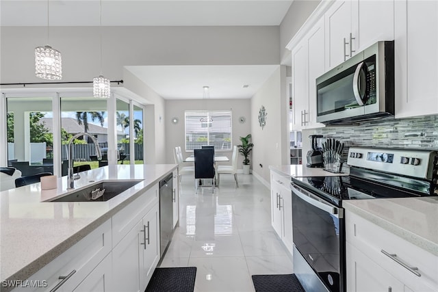 kitchen featuring white cabinets, plenty of natural light, pendant lighting, and stainless steel appliances