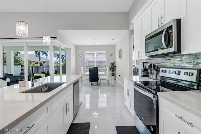 kitchen featuring decorative backsplash, appliances with stainless steel finishes, pendant lighting, and a sink