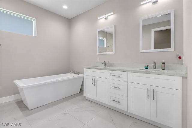 bathroom featuring double vanity, a freestanding tub, marble finish floor, and a sink