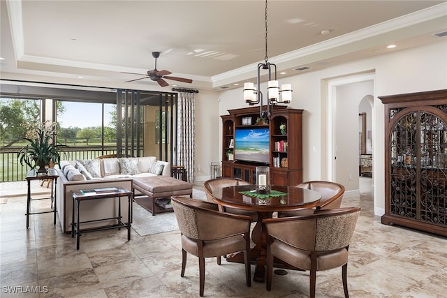 dining area with ceiling fan with notable chandelier, a tray ceiling, and crown molding