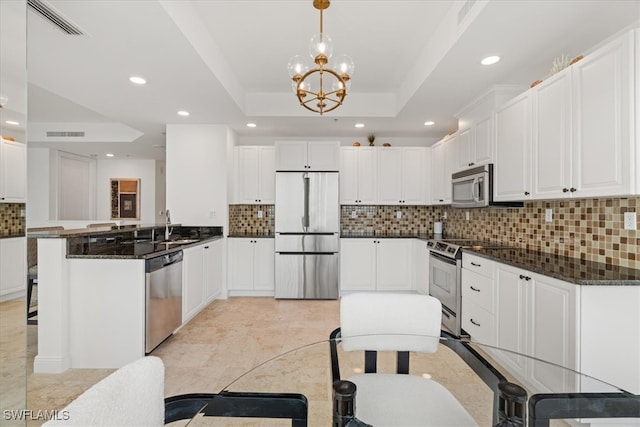 kitchen featuring hanging light fixtures, stainless steel appliances, kitchen peninsula, a tray ceiling, and white cabinets