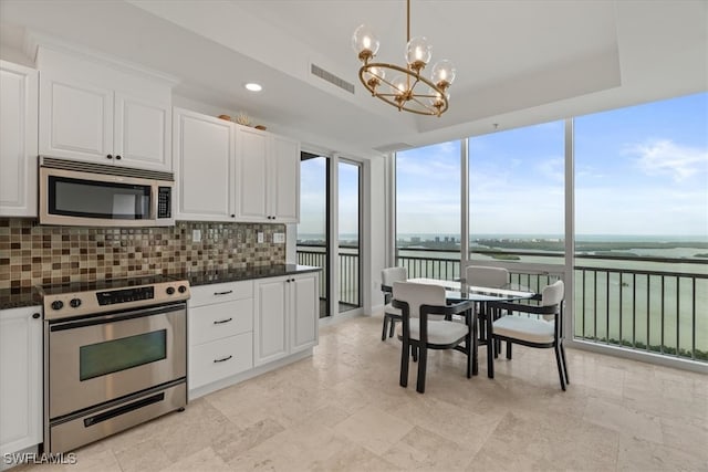 kitchen featuring tasteful backsplash, decorative light fixtures, white cabinetry, stainless steel appliances, and a chandelier