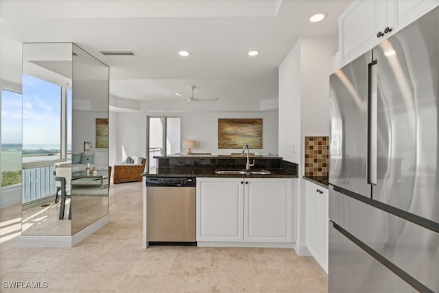 kitchen featuring ceiling fan, sink, stainless steel appliances, dark stone countertops, and white cabinets