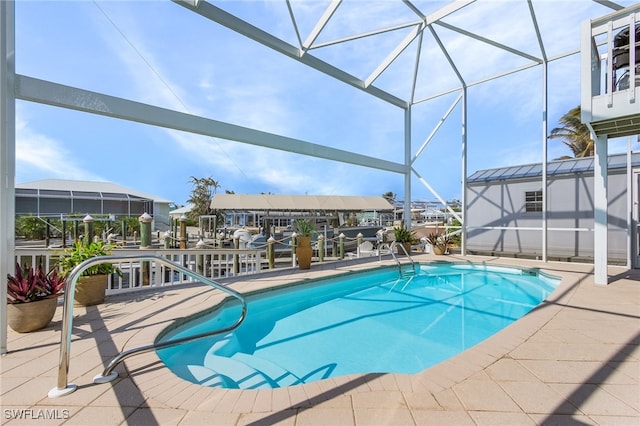 view of pool featuring glass enclosure, a storage shed, and a patio