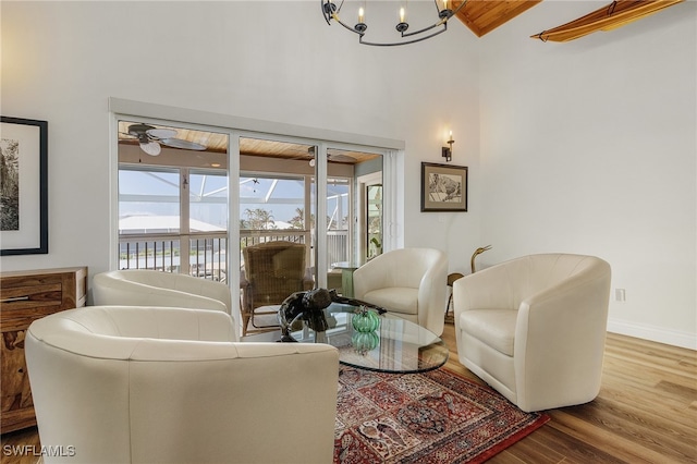 living room featuring hardwood / wood-style floors, ceiling fan with notable chandelier, and beam ceiling