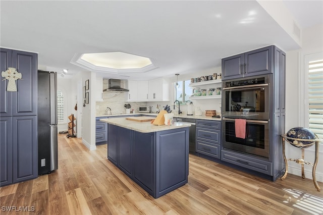 kitchen featuring wall chimney exhaust hood, plenty of natural light, a center island, and appliances with stainless steel finishes