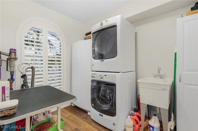 laundry room with stacked washing maching and dryer, light hardwood / wood-style flooring, and water heater