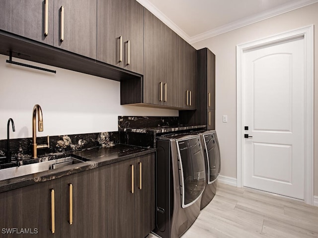 clothes washing area featuring sink, cabinets, separate washer and dryer, crown molding, and light hardwood / wood-style floors